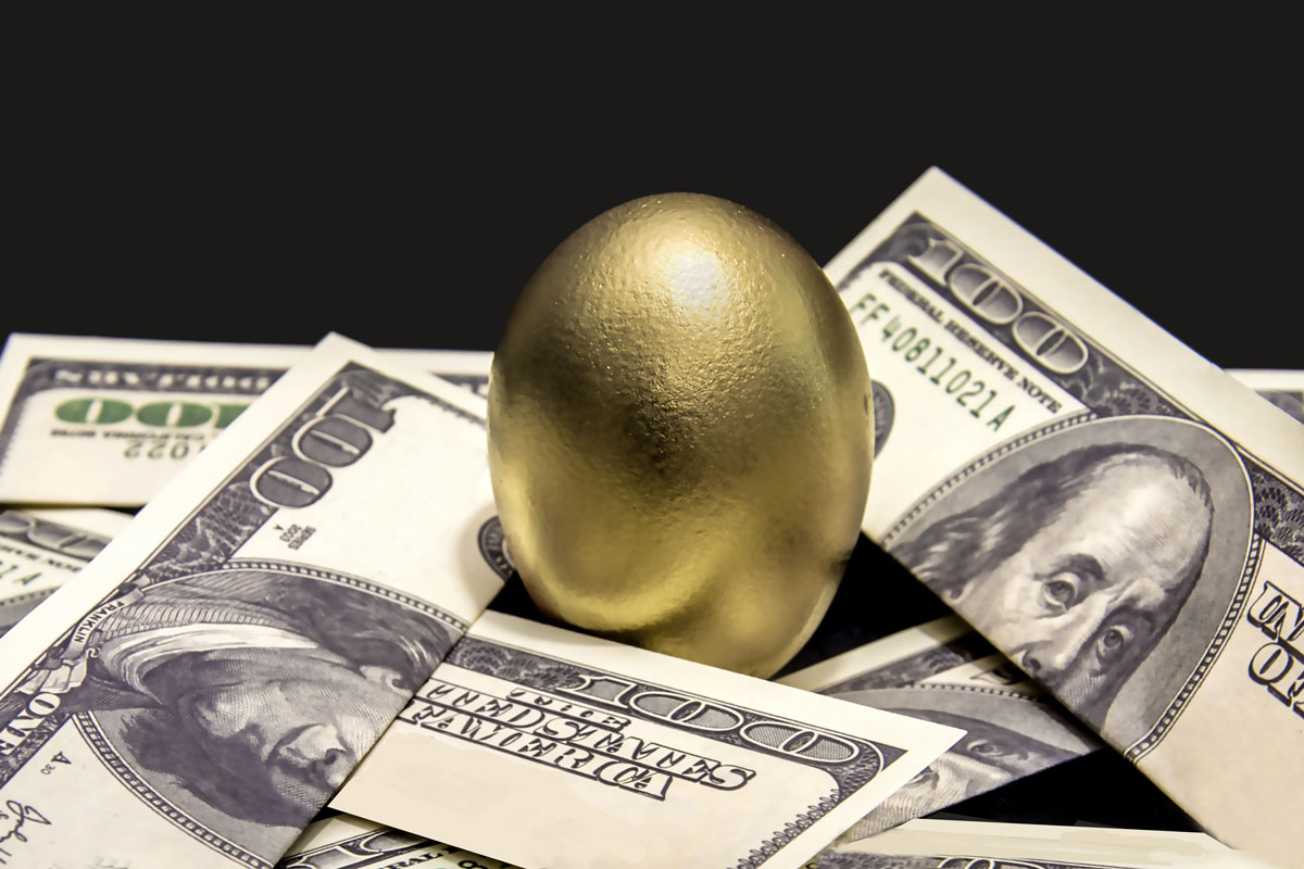 photo of a golden nest egg resting on top of several one hundred dollar bills